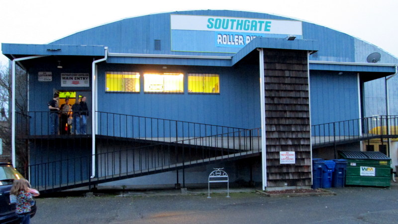 Southgate Roller Rink in White Center, a blue barrel-roofed building with its sign lit and windows glowing at dusk